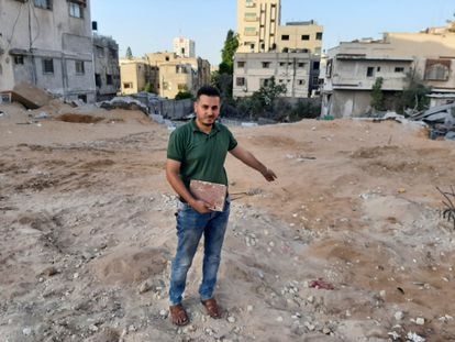 El librero Shaban Eslim señala el lugar donde se encontraba su librería, destruida por los bombardeos israelíes, con un Corán rescatado de entre los escombros, el día 9 de septiembre en Gaza. 