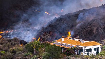 La lava del volcán de La Palma cerca de una vivienda este martes.