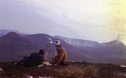 Dos hombres con cámaras sobre trípodes juegan al ajedrez tras la erupción del volcán Teneguía en la isla de La Palma en 1971.