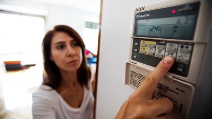 Una mujer acciona el panel del aire acondicionado en su vivienda.