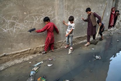 Niños tratan de pasar por una calle en la que se ha vaciado una fosa séptica en un barrio próximo a la zona de Sarai Shamali de Kabul.                            
