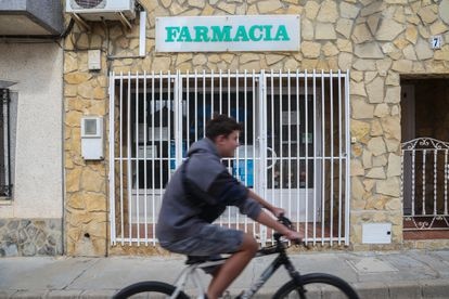 Un chaval en bicicleta pasa por delante de la farmacia de Balsa de Ves, cerrada permanentemente. 