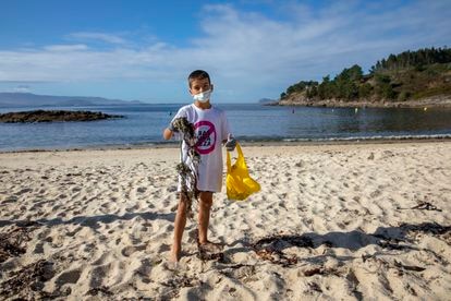 Héctor Osorio, de ocho años, muestra la basura que ha recogido en la playa de Limens (Pontevedra).