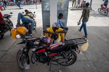 Personas hacen guardia a la espera de combustible en una gasolinera cerrada en Puerto Príncipe.