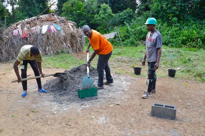 Tres jóvenes baka desbrozan el terreno sobre el que se construirá una escuela.