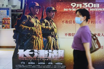 Una mujer pasa delante del cartel de la película 'La batalla de Changjin' en la región de Zhejiang.