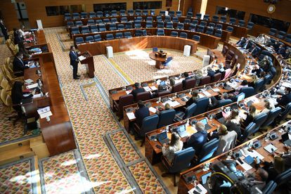 El portavoz adjunto del PP en la Asamblea de Madrid, Pedro Muñoz Abrines, habla en el pleno, con los escaños vacíos de la oposición.