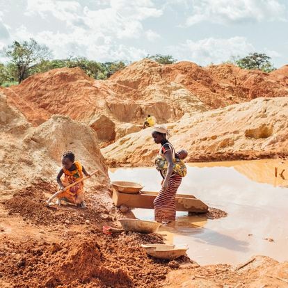 Una madre con su bebé en la espalda y su hija mayor trabajan buscando oro en una mina ilegal en Beke Route, este de Camerún