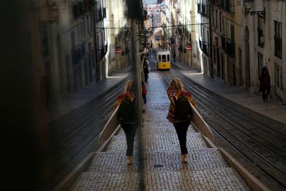 Una mujer camina con una tabla de surf por una calle de Lisboa, este viernes.