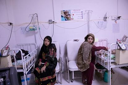 Dos madres jóvenes cuidan de sus hijos desnutridos en la clínica de alimentación terapéutica en Herat.