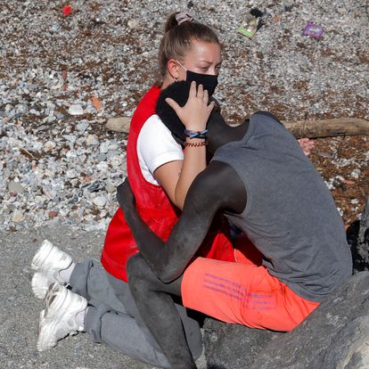 Luna Reyes, 20, a member of Spanish Red Cross, embraces and comforts a migrant Sub-Saharian as he refuses to be deported to Morocco after he crossed the border swimming from Morocco to Spain, at El Tarajal beach, after thousands of migrants swam across this border during last days, in Ceuta, Spain, May 18, 2021. Picture taken May 18, 2021. REUTERS/Jon Nazca - RC2FIN9JWNV3