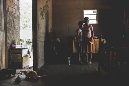 La señora Silva con uno de sus nietos en la sala cocina de su casa de ladrillo y suelo de tierra, en Garanhuns (Pernambuco).