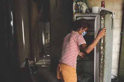 Maria Helena da Silva, ante la fresquera de su casa, donde viven 11 personas sin electricidad ni agua. 