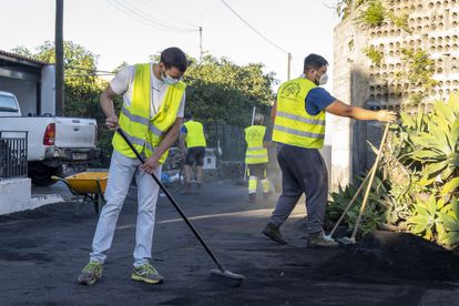Varias personas limpian las inmediaciones de una casa, este lunes en La Palma. 