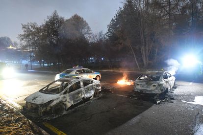 Varios coches de policía tras se quemados durante las protestas en Almaty, este miércoles