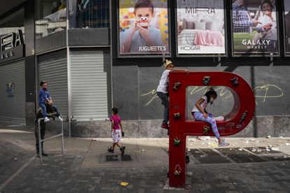 Un grupo de niños juega en la P de un cartel de PDVSA en las calles de Caracas el 2 de enero.