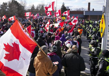 Los agentes forman un cordón policial frente a los manifestantes que apoyan a los camioneros que bloquearon el tráfico del puente Ambassador en Windsor, Ontario.