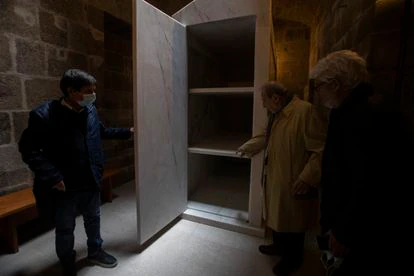 Siza muestra el interior del túmulo proyectado mientras el marmolista que lo fabricó abre la puerta.