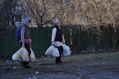 Dos mujeres regresan a casa en el día en que miles de personas han hecho cola en los supermercados de Kiev para comprar comida ante el riesgo al desabastecimiento.