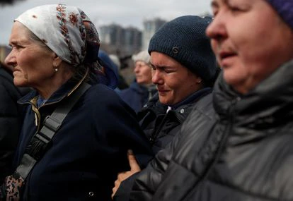 Tres mujeres tratan de reconocer a sus familiares entre los cadáveres de civiles hallados en la localidad de Bucha, al noroeste de Kiev, el 8 de abril. 