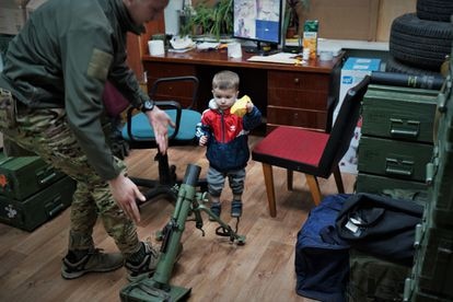 El hijo de un comandante del Batallón Azov en un almacén de armas junto a un miliciano en una base de este movimiento en Kiev.