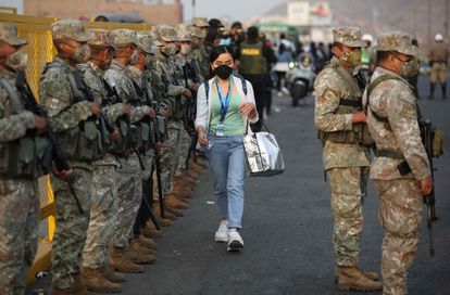 Durante las primeras horas del toque de queda, una mujer camina entre un cerco militar en Lima, este martes.