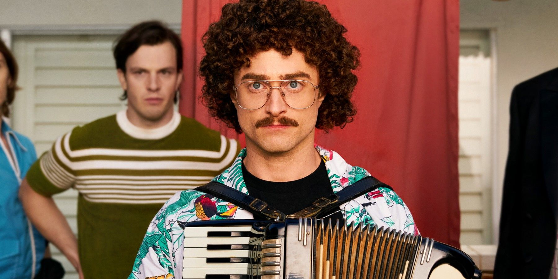Daniel Radcliffe holding an accordian and staring intensely at camera in Weird The Al Yankovic Story