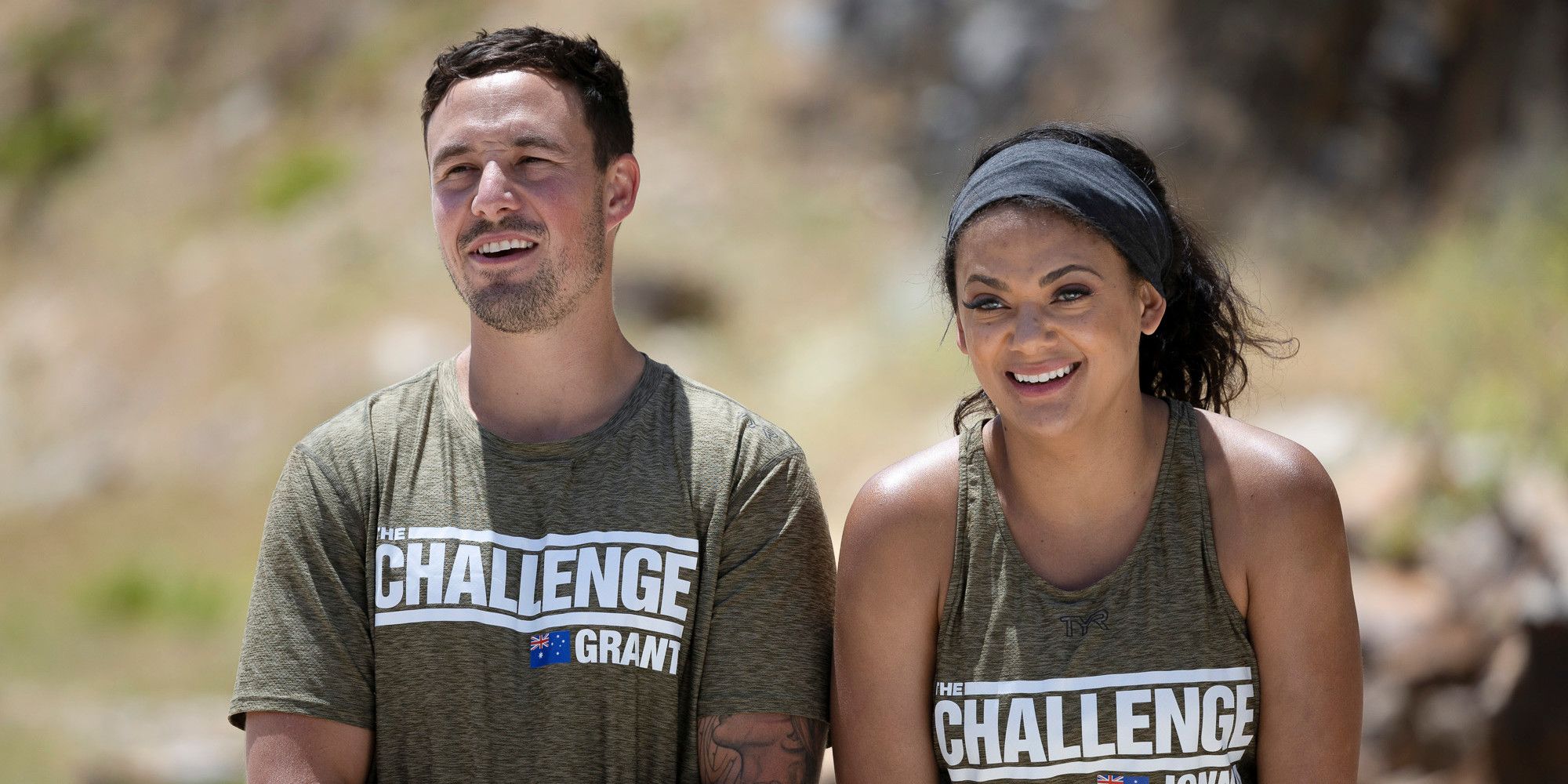 Grant Crapp and Jonna Mannion on The Challenge. They are standing side by side and smiling, wearing matching shirts with The Challenge logo and the Australian flag on them.