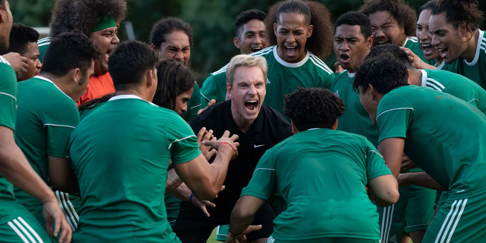 Michael Fassbender as Thomas Rongen yelling and surrounded by team in Next Goal Wins