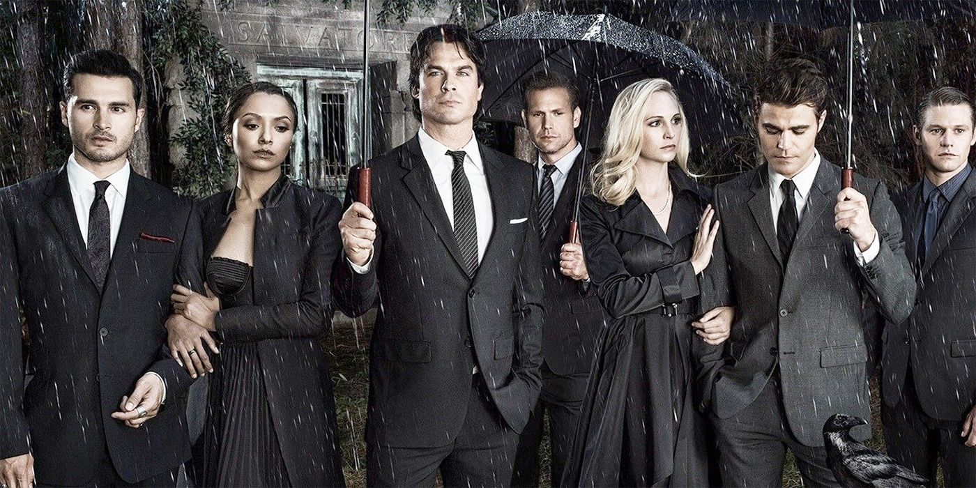 The Vampire Diaries cast wearing black and holding umbrellas in the rain