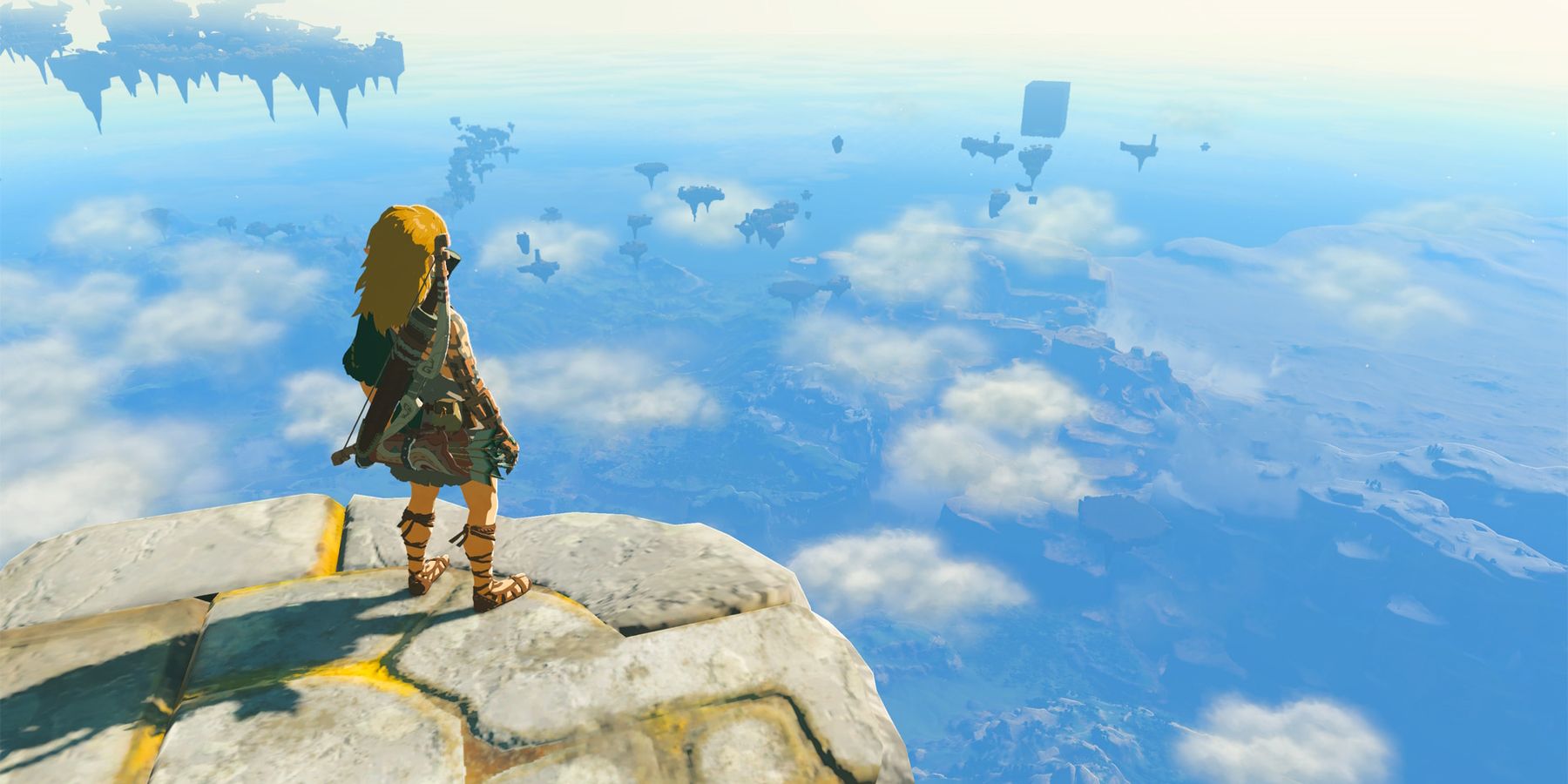 Zelda TOTK Sky Islands, Link with a bow on his back standing on a paved stone surface overlooking some of the sky islands and world down below