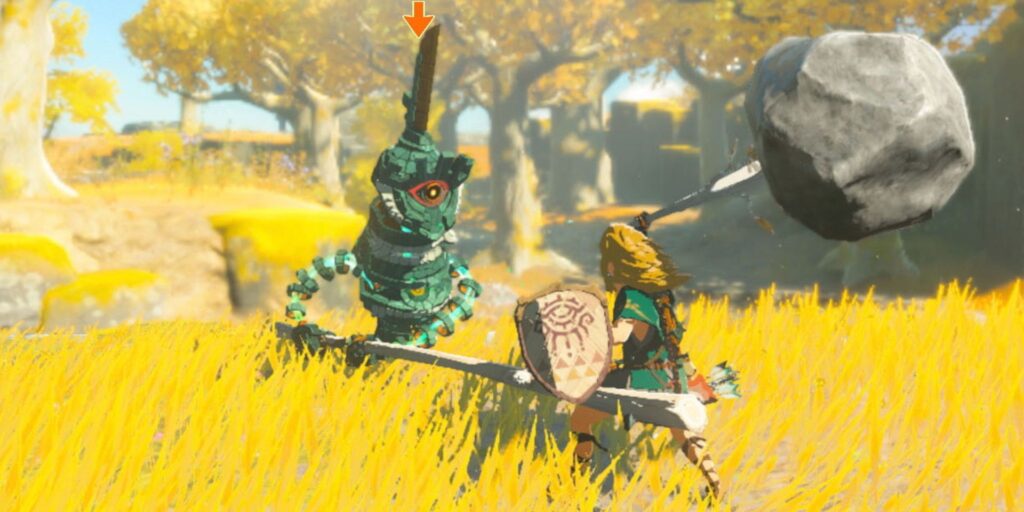 Link swings a boulder-tipped sword at a mechanical construct enemy in a grassy field in The Legend of Zelda: Tears of the Kingdom.