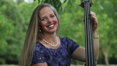 Welcome to Plathville's Kim Plath smiling holding a cello