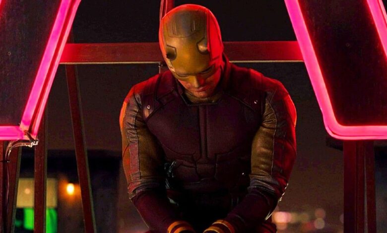 Daredevil sitting in front of a neon sign.