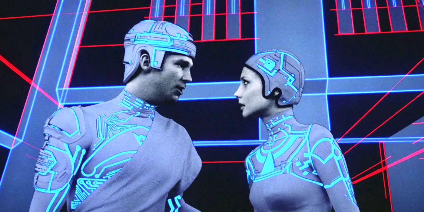 Jeff Bridges and Cindy Morgan in TRON wearing tight gray costumes with glowing light blue elements mimicking computer circuits, having an intense conversation in front of a colorful laser-light style backdrop