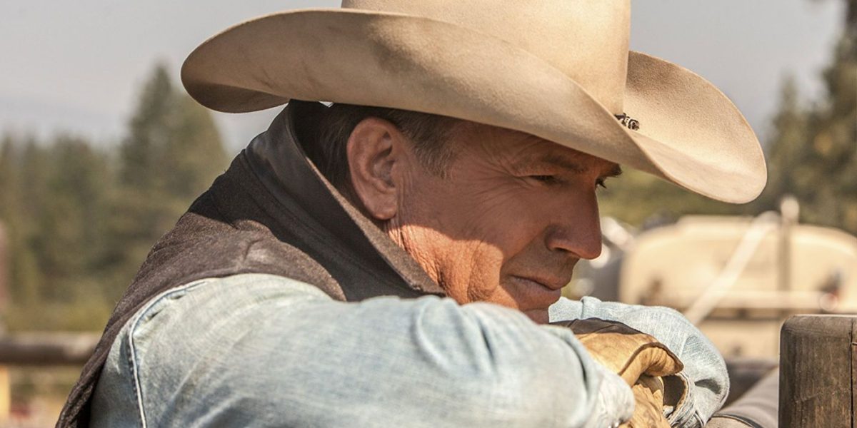 Kevin Costner with his head on top of a ranch fence in Yellowstone