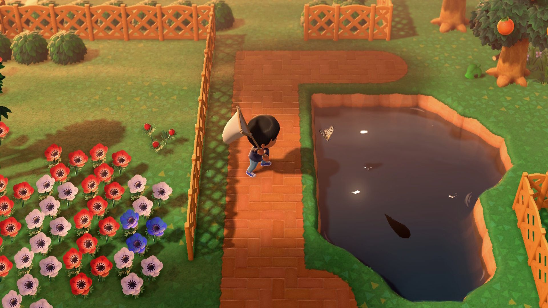 El jugador de Animal Crossing New Horizons se prepara para atrapar una mariposa sobre un estanque al atardecer