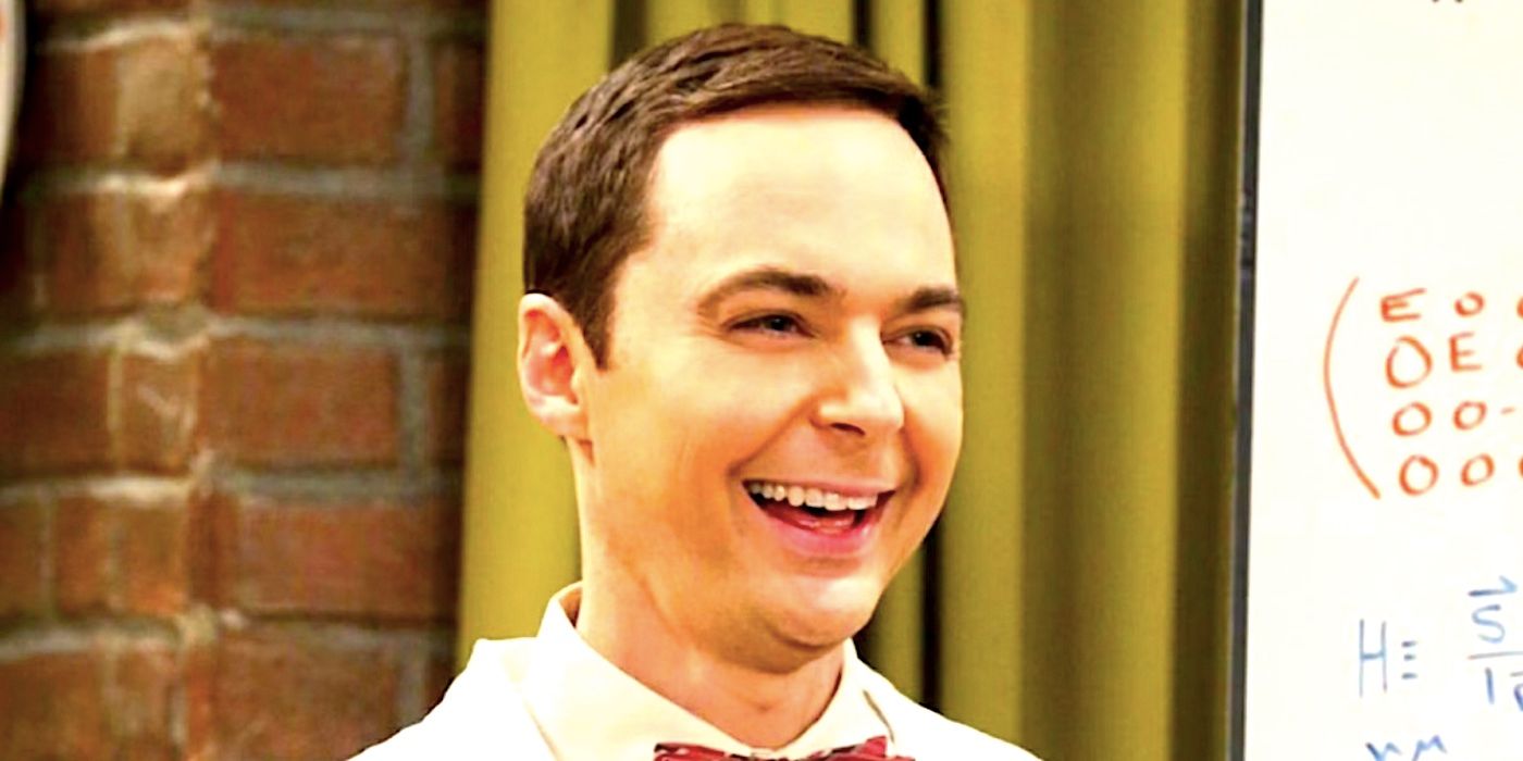 Sheldon Cooper sonriendo y riendo mientras llevaba una pajarita frente a una pizarra blanca en The Big Bang Theory
