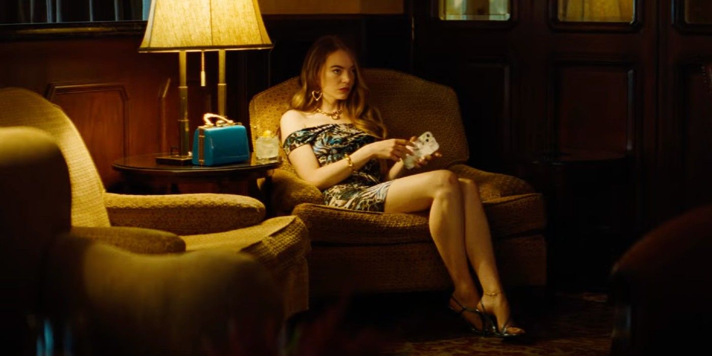 Emma Stone sentada en una silla en una habitación con poca luz en el tráiler del tipo de bondad.