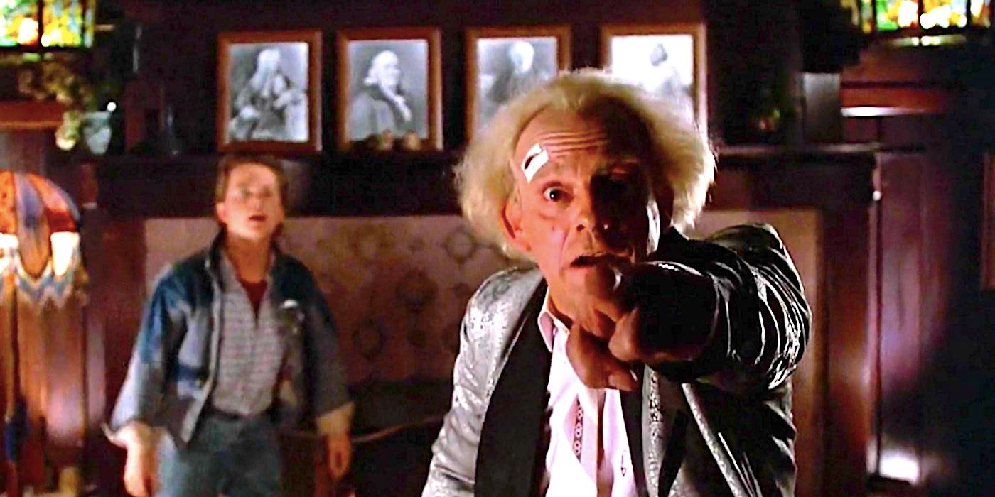 Doc Brown (Christopher Lloyd) apunta a la cámara mientras Marty (Michael J. Fox) mira al fondo en Regreso al futuro.