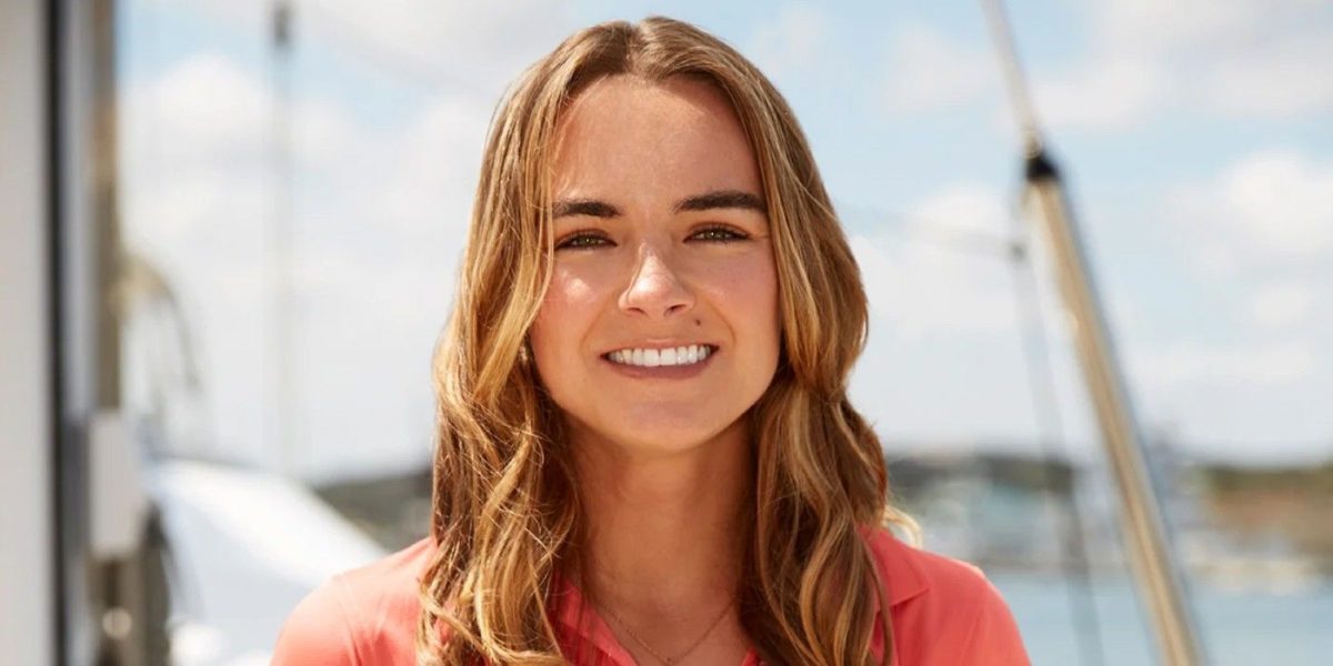 Kelsie Goglia Below Deck Sailing Yacht, orange top, with ocean and boat in background