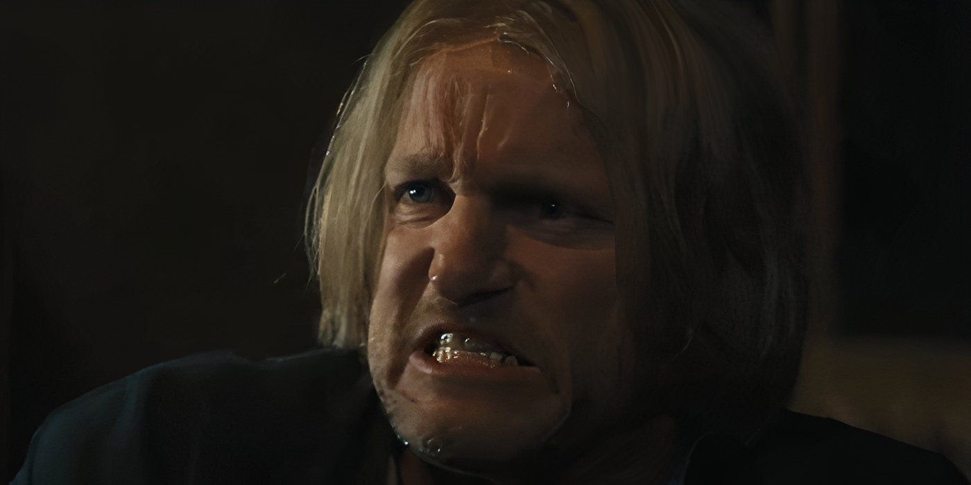 Haymitch, interpretado por Woody Harrelson, está visiblemente enojado y aprieta la mandíbula ante la noticia del Vasallaje de los Veinticinco.