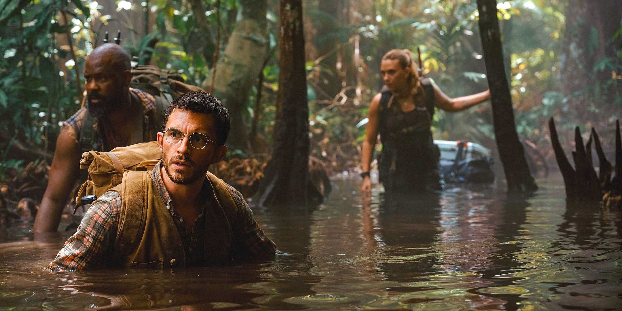 El Dr. Henry Loomis (Jonathan Bailey), un hombre (Bechir Sylvain) y Zora Bennett (Scarlett Johansson) caminando por un pantano que explora la isla de los dinosaurios en el renacimiento mundial jurásico