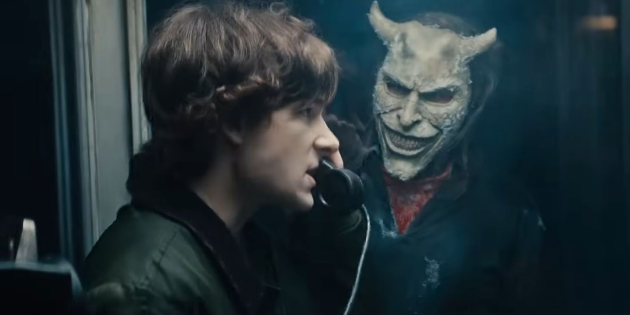 Finn de Mason Thames luce enojado mientras estaba por teléfono mientras el Grabber de Ethan Hawke mira desde fuera de la cabina de teléfono en Black Phone 2
