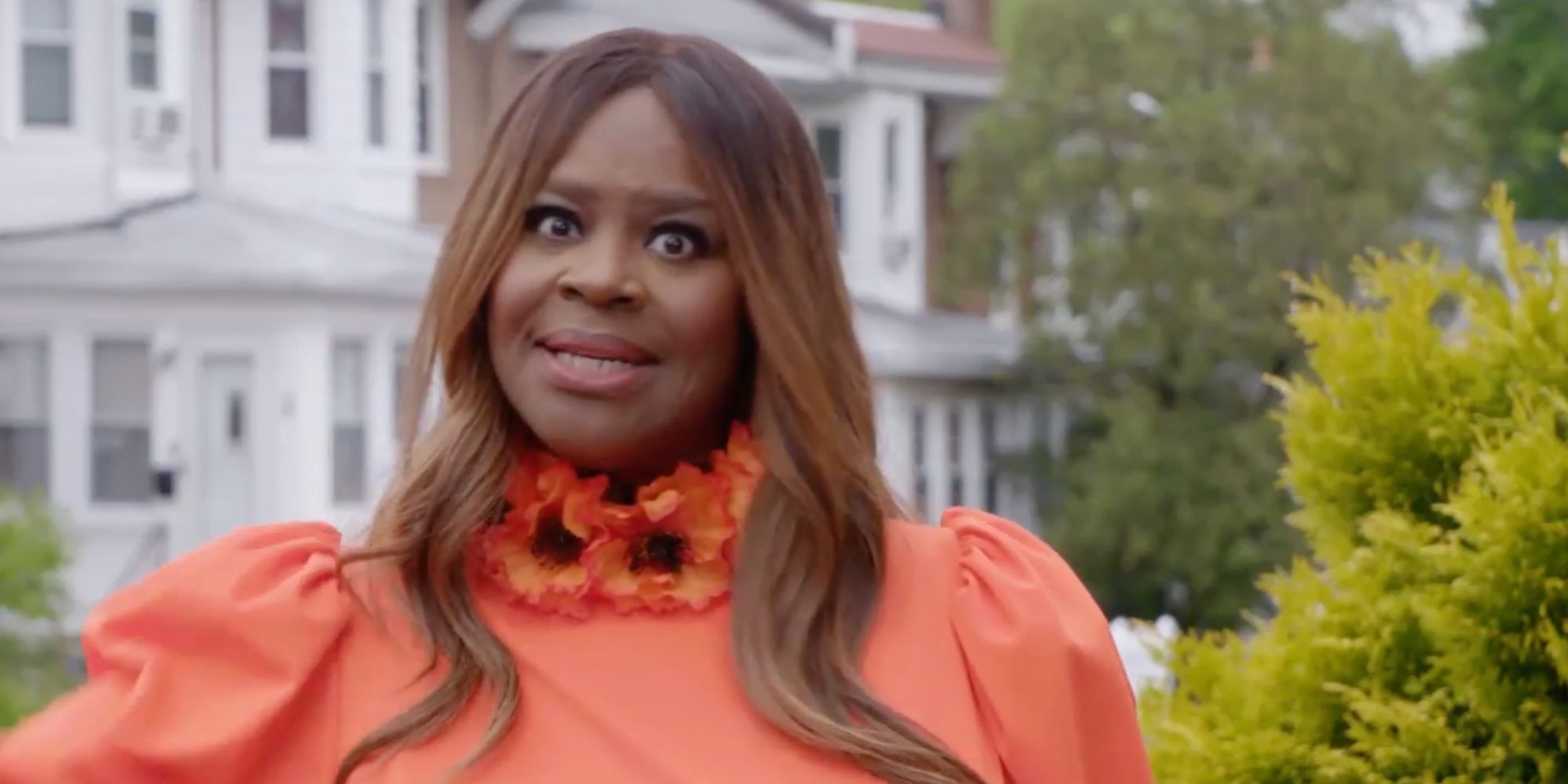 House más fea de América Retta de ojos muy abiertos con un vestido de naranja afuera